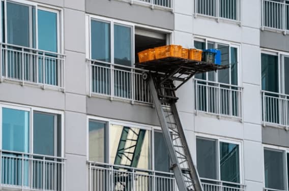 Un'autoscala con piattaforma ferma alla finestre di un appartamento pronta per caricare i detriti